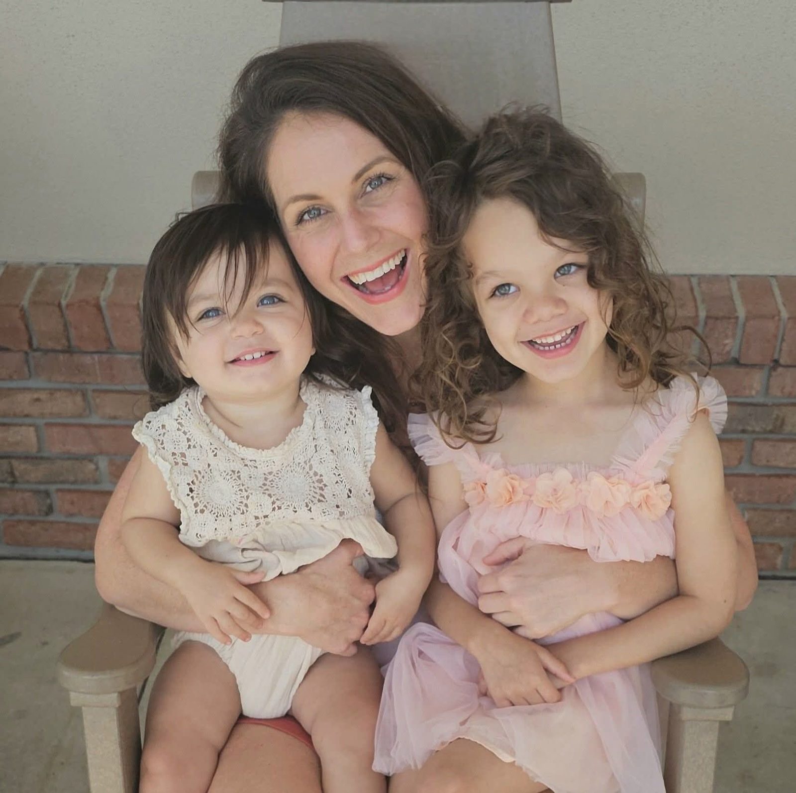 Sarah hugging both daughters on a porch chair