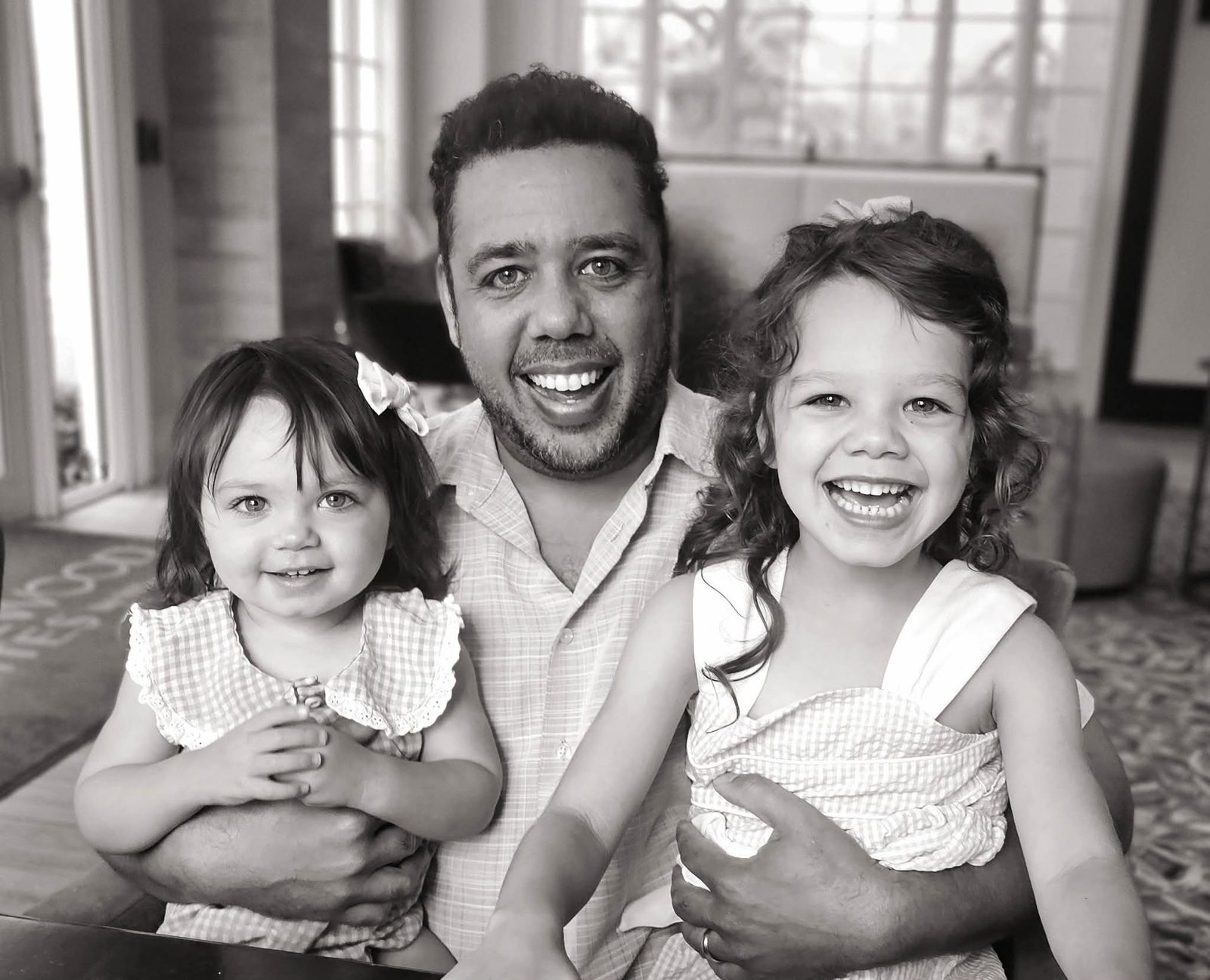 Dad laughing with both daughters, black and white