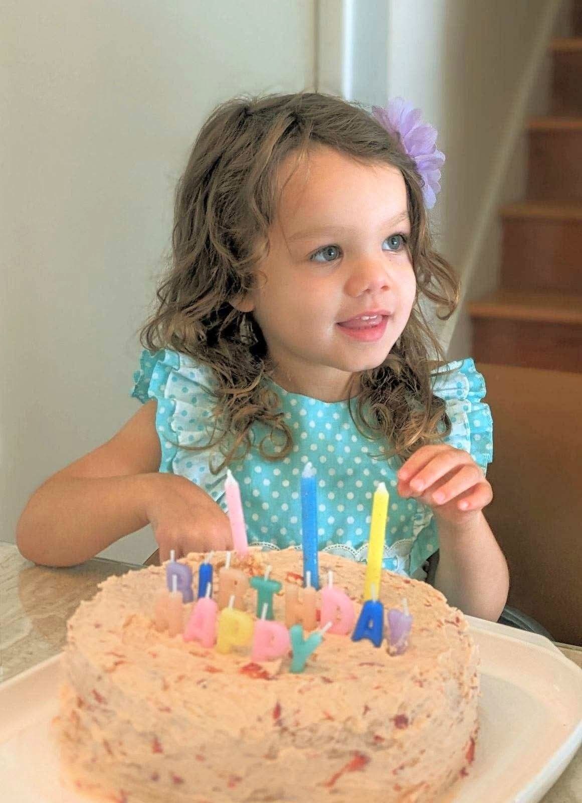 Toddler smiling behind a homemade birthday cake