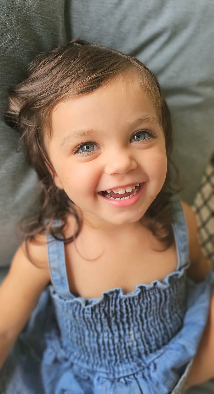 Toddler grinning in a denim sundress