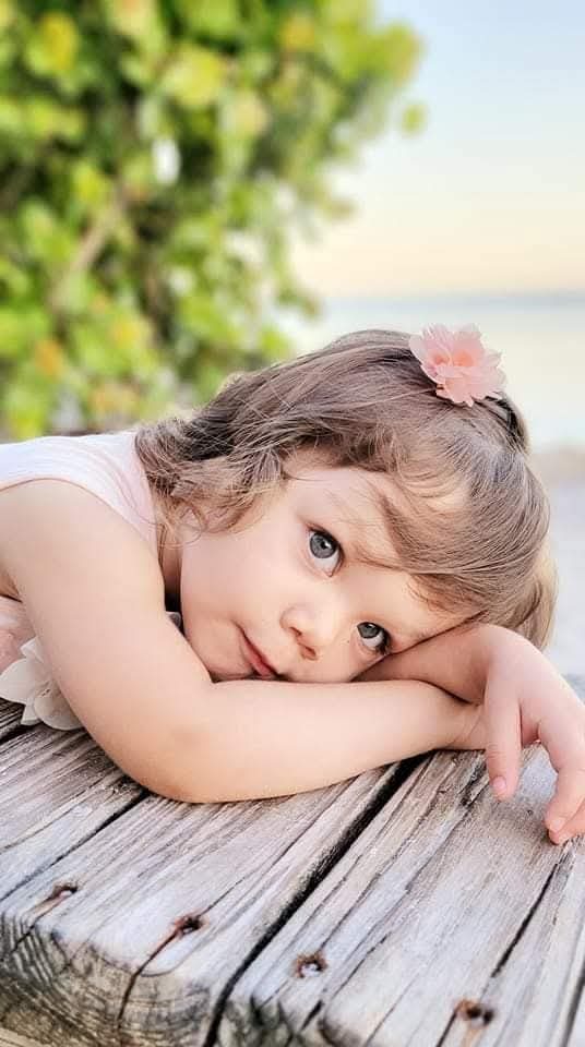 Toddler resting her head on a wooden dock by the water