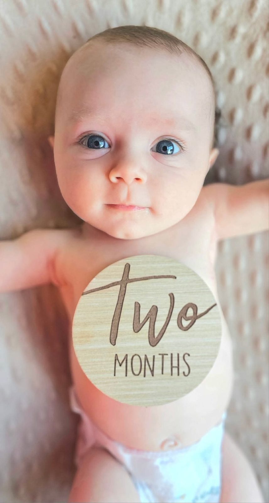 Baby holding a two months milestone sign
