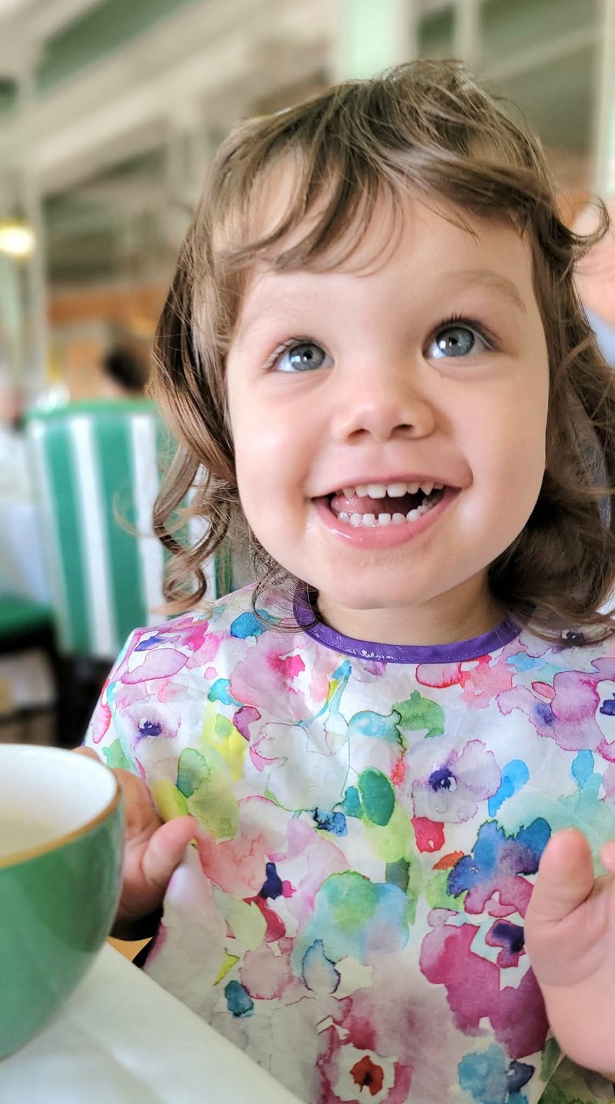 Toddler grinning at a tea table