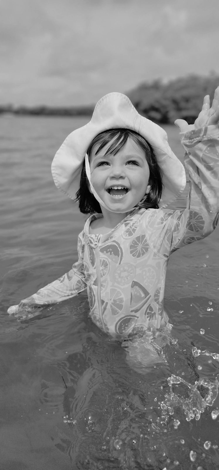 Toddler laughing and splashing in the water, black and white