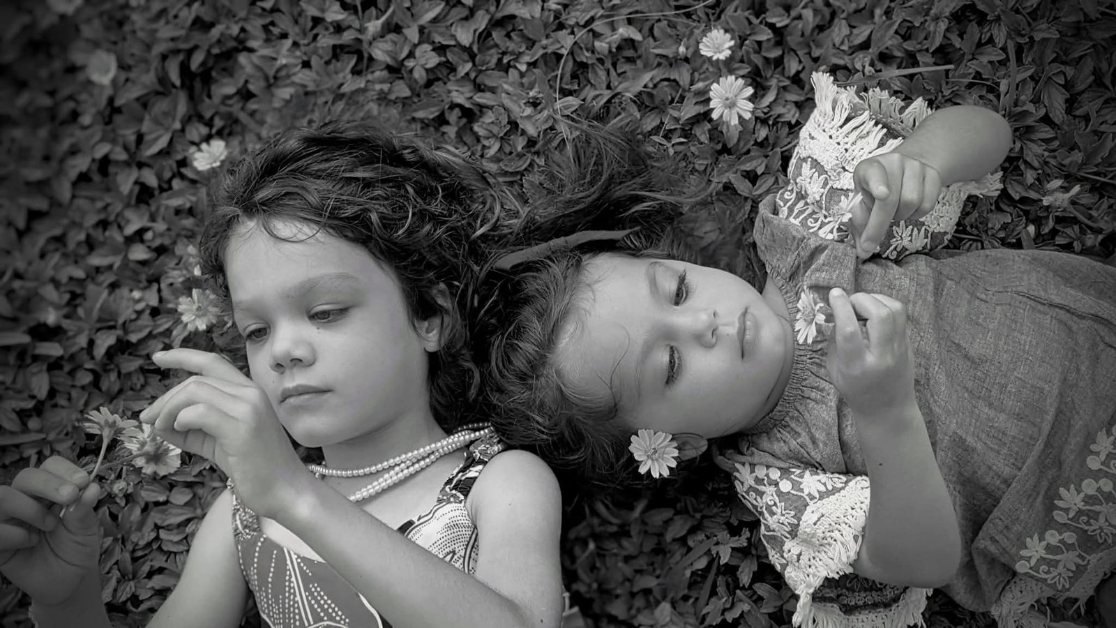 Two sisters lying in flowers, black and white