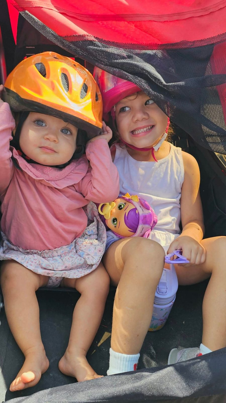Sisters in bike helmets in a trailer